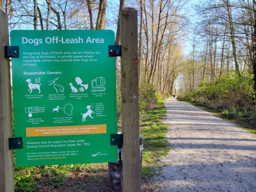 A trail with a sign next to it designating it an off-leash area