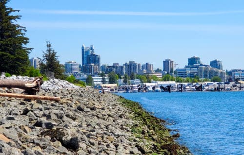 An east facing picture of the rocky shorline with the mosquito creek marina and city in the backdrop at kings mill walk off-leash dog park, north vancouver, bc