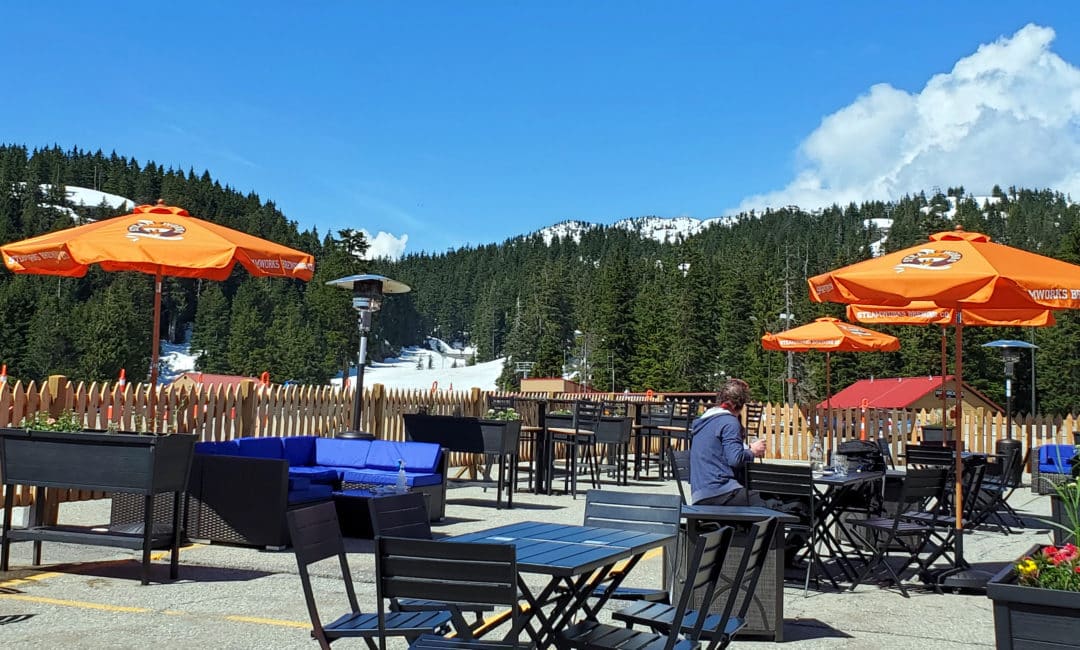 A picture of the dog-friendly patio with snow covered ski runs in the background at the rock chute kitchen and bar patio on mount seymour, north vancouver, bc